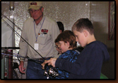 Vic Oma and Ed Naylor assist kids fishing at the Berkley Kids Aquarium at the 2009 Sports Show in Rapid City.