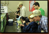 Ed Naylor and Vic Oma help kids at the free fishing aquarium at the 2009 Sports Show in Rapid City.