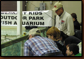 Ed Naylor and Vic Oma help kids at the free fishing aquarium at the 2009 Sports Show in Rapid City.