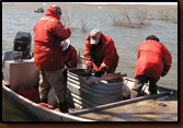 Mike Johnson (far right) releases a tagged walleye while Denny Bohls places the next fish in the measuring trough. Rick Zimbelman (far left) prepares to tag the fish and Nancy Smidt records information. Volunteers assisted GF&P in this project at Orman Dam.
