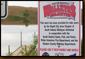 A view of the sign at Waggoner Lake with the dock in the background.